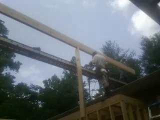 Carpenter setting a ridge beam over a new addition frame — Ice Dam Removal by Roofing Brothers in Barney