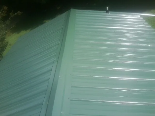 New green metal panels meeting at the ridge of a roof — Flat Roof Repair work by our crew in Barney