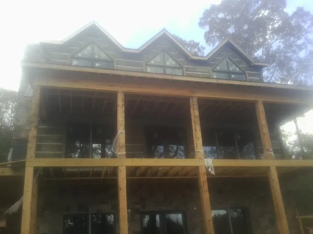 Dormers and porch framing on a large log home under construction — Roof Coating work by our crew in Barney